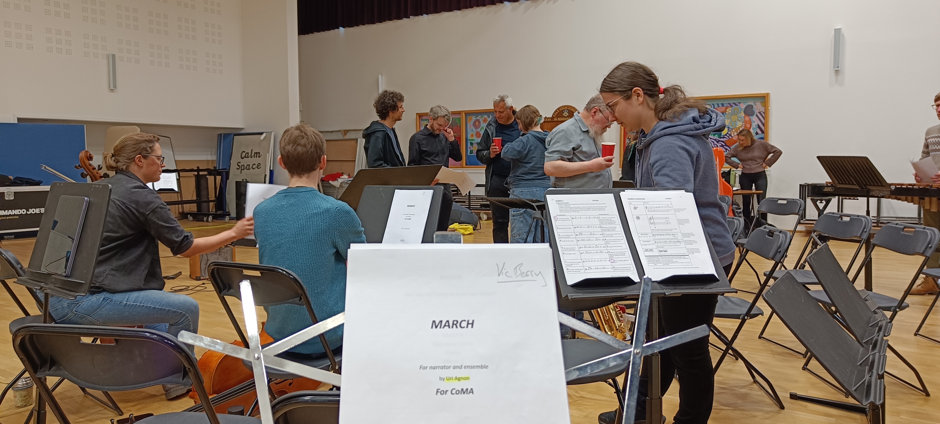 The title page in the foreground with the composer and conductor stood in the background, other musician are setting up