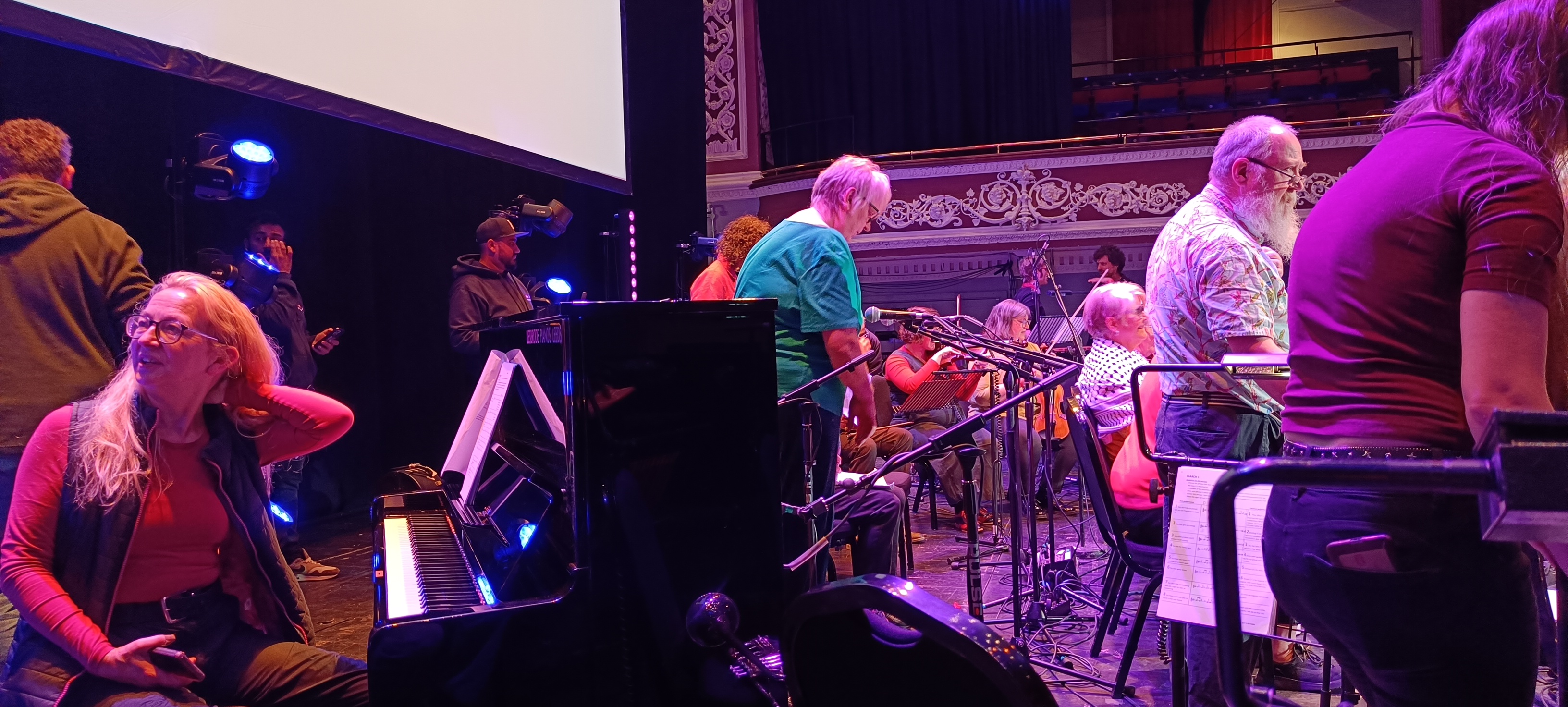 Musicians are setting up on stage a piano is in the foreground