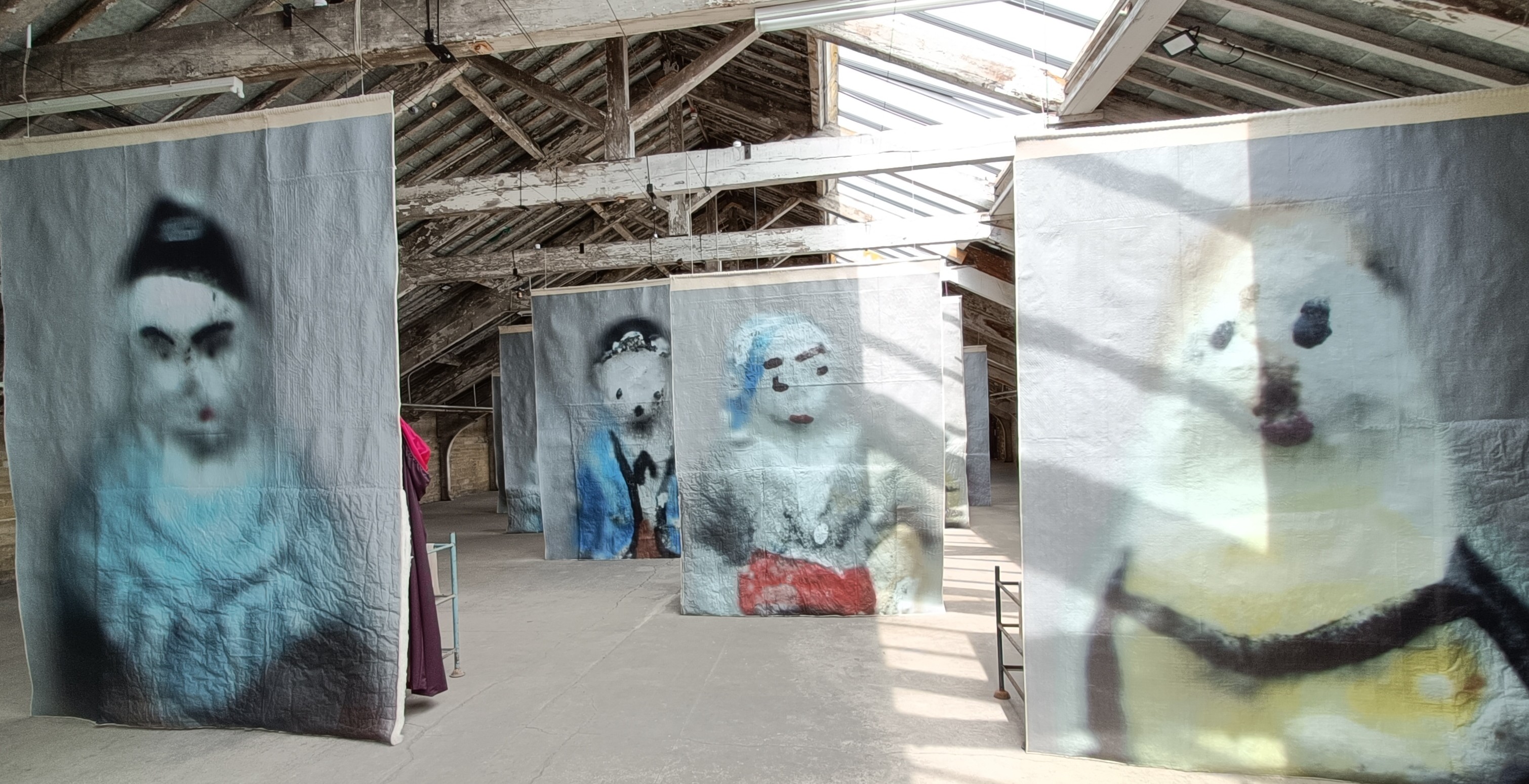View burred figures printed on suspended artwork in the exhibition hall