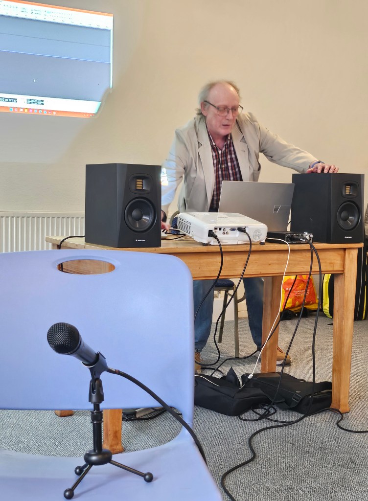 Facilitator demonstrating editing techniques on overhead screen, laptop and stereo audio speakers.